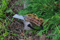 Banzelcroft Customs MEK, a titanium EDC utility knife with stabilized curly koa handle scales and canvas micarta liners.