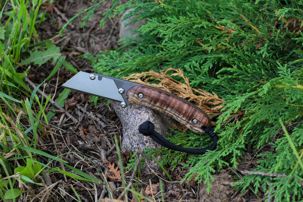 Banzelcroft Customs MEK, a titanium EDC utility knife with stabilized curly koa handle scales and canvas micarta liners.