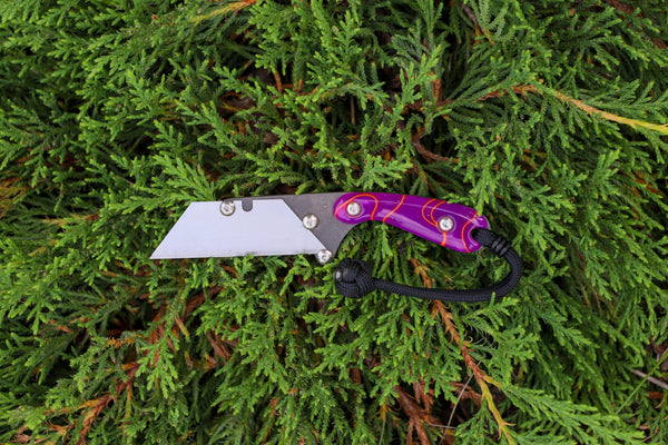 Banzelcroft Customs MEK, a custom titanium EDC utility knife with purple and orange acrylic handle scales.