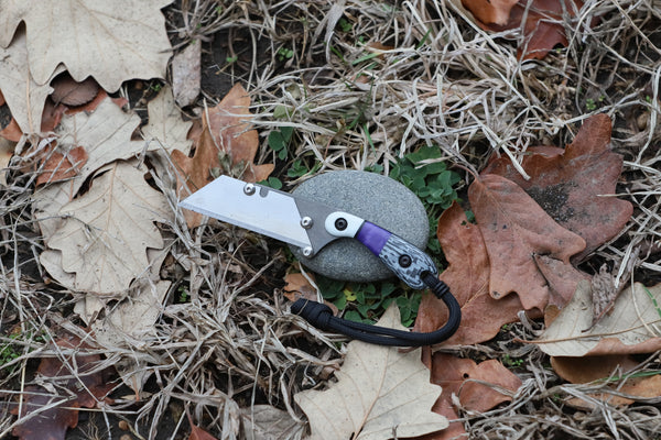 Banzelcroft Customs MEK, a custom titanium EDC utility knife with white G10, purple juma, and carbon fiber handle scales.