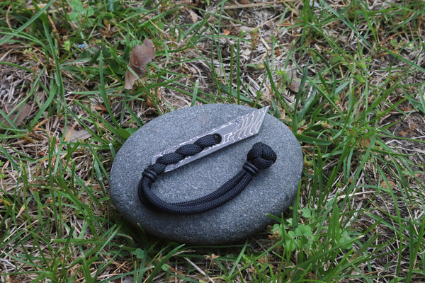 Banzelcroft Customs Nano kiridashi, a small fixed blade for everyday cutting tasks made from virus damascus and black paracord.