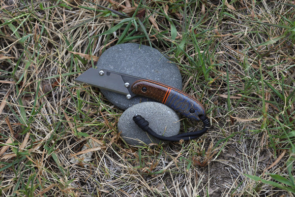 Banzelcroft Customs MEK, a titanium EDC utility knife with burlap micarta, nightmare crazy fiber, and orange liners.
