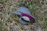 Banzelcroft Customs MEK, a custom titanium EDC utility knife with magenta bliss acrylic handle scales and brass liners.